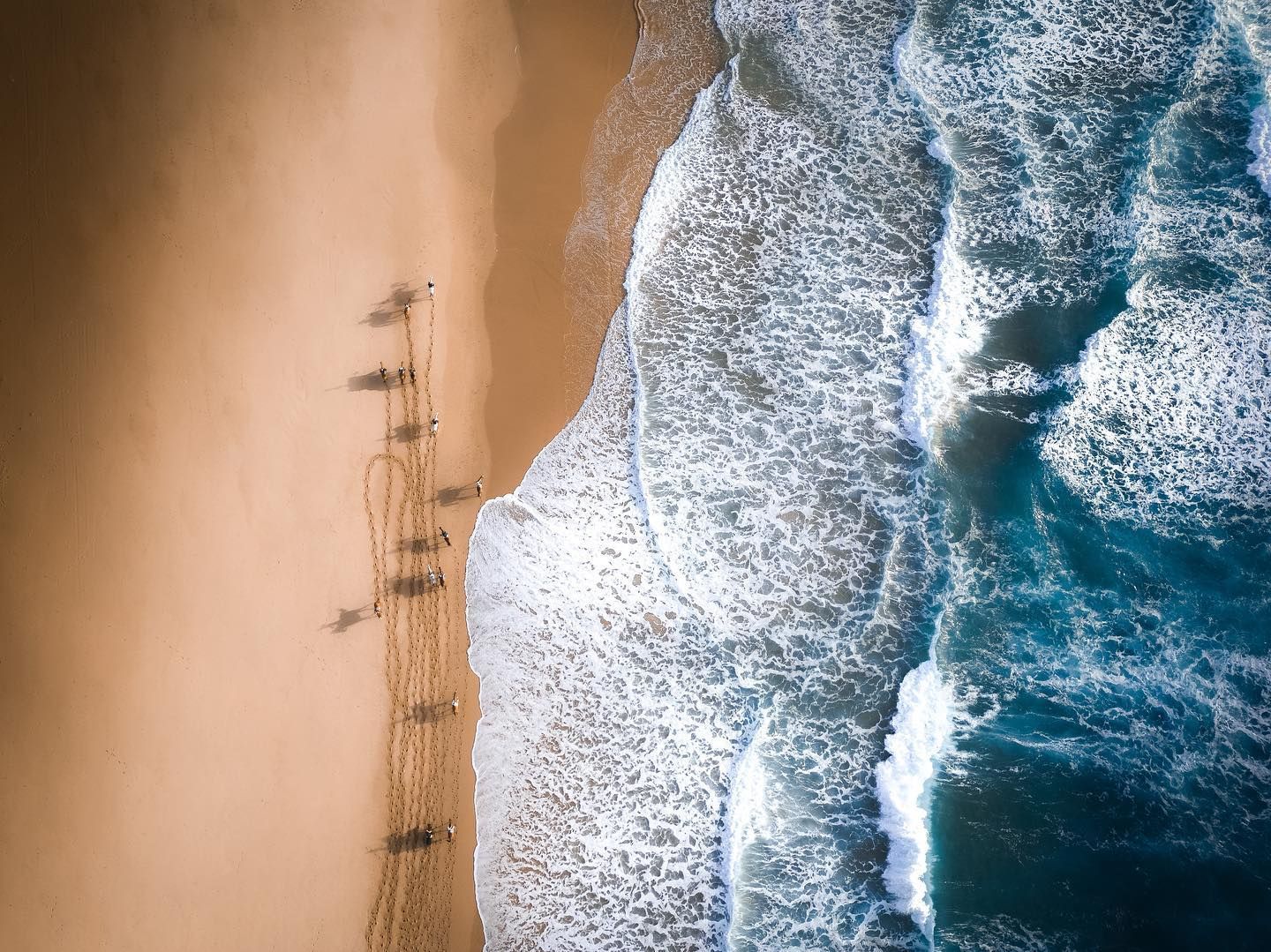 An aerial view of a beach with waves crashing on the shore.