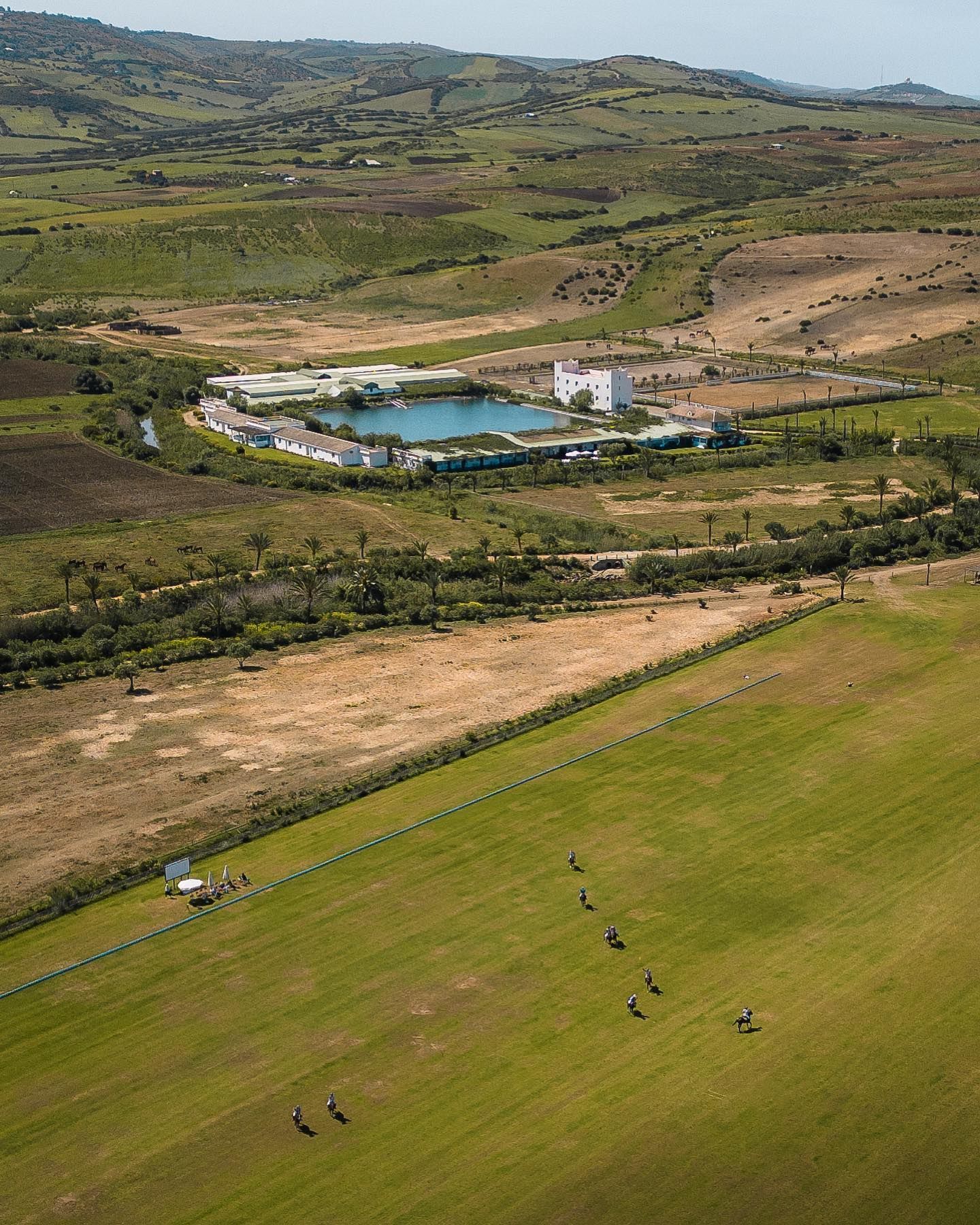 An aerial view of a lush green field with a large body of water in the middle.