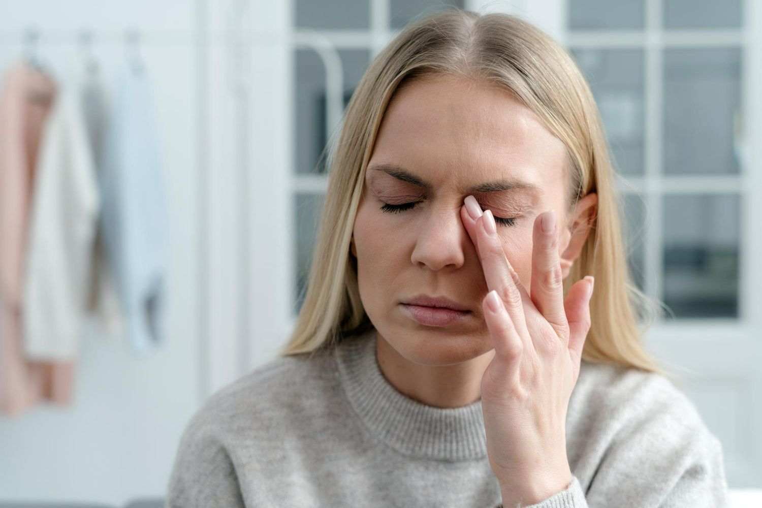 A woman is holding her nose because she has a headache.