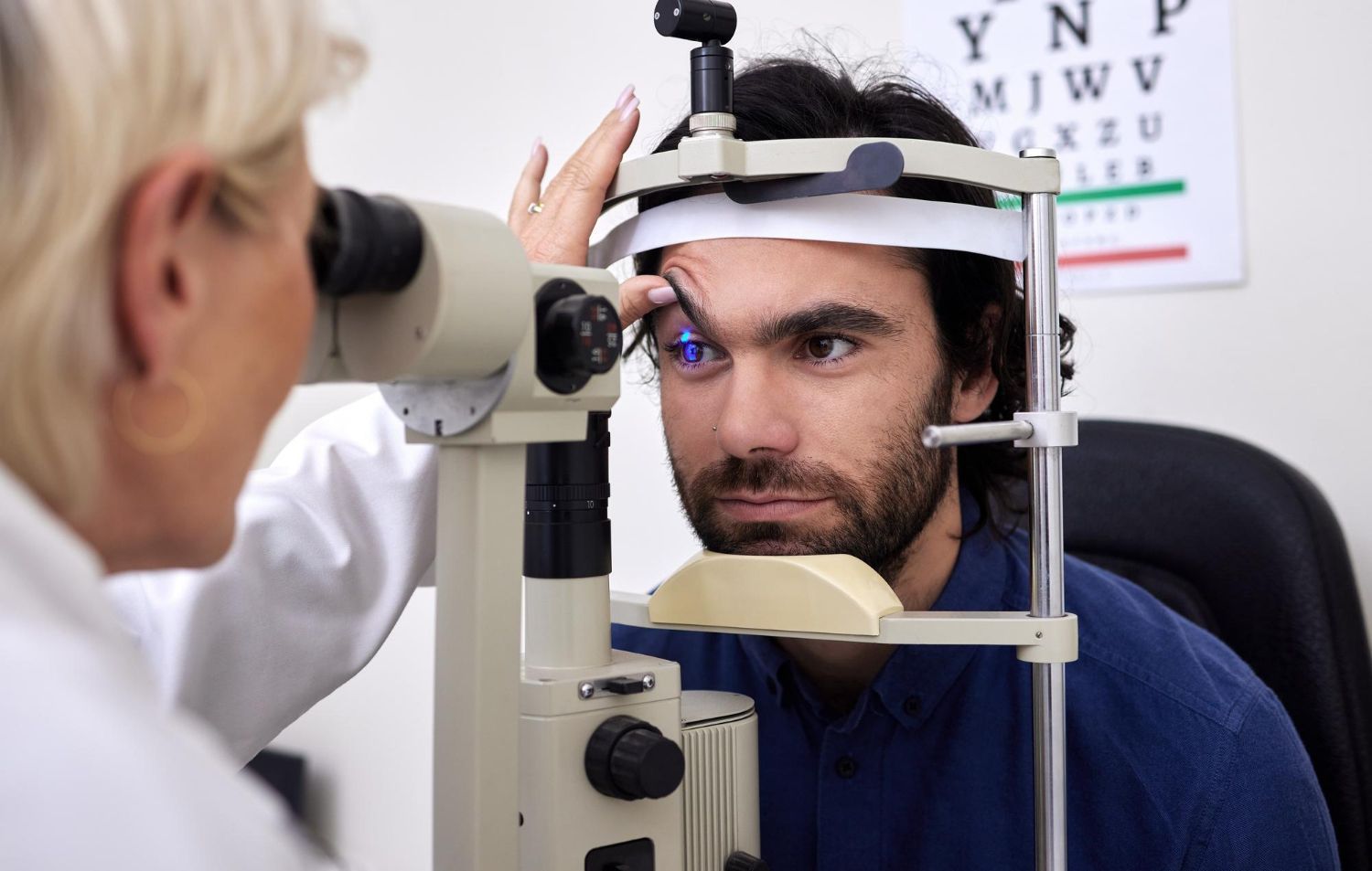 Optometrist examines a patient's eye with a slit lamp in an eye clinic.