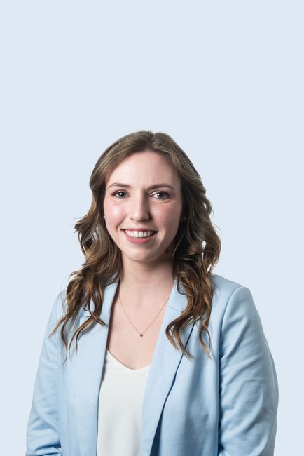 A woman in a blue jacket and white shirt is smiling for the camera.