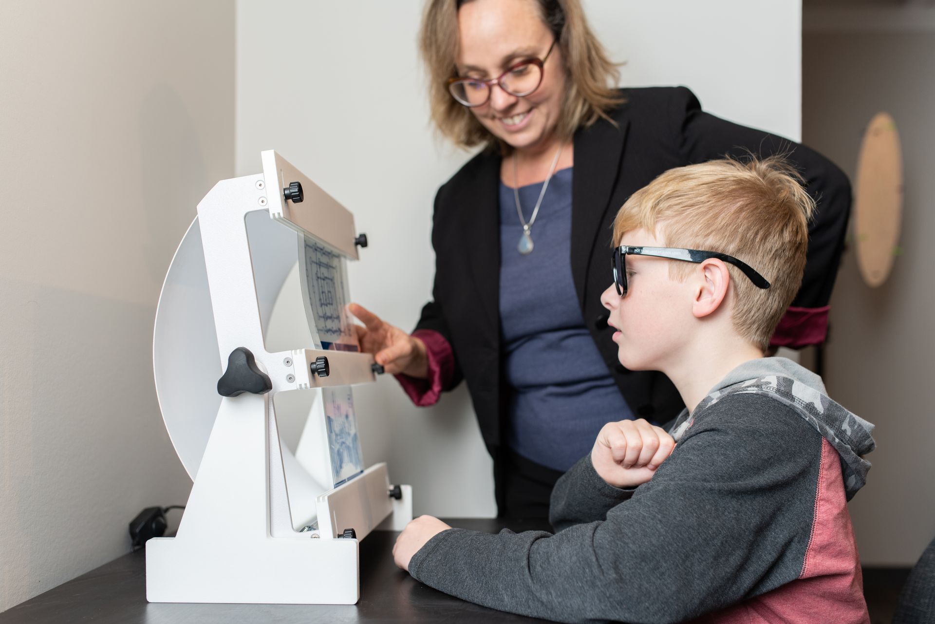 A woman is teaching a boy how to use a machine.