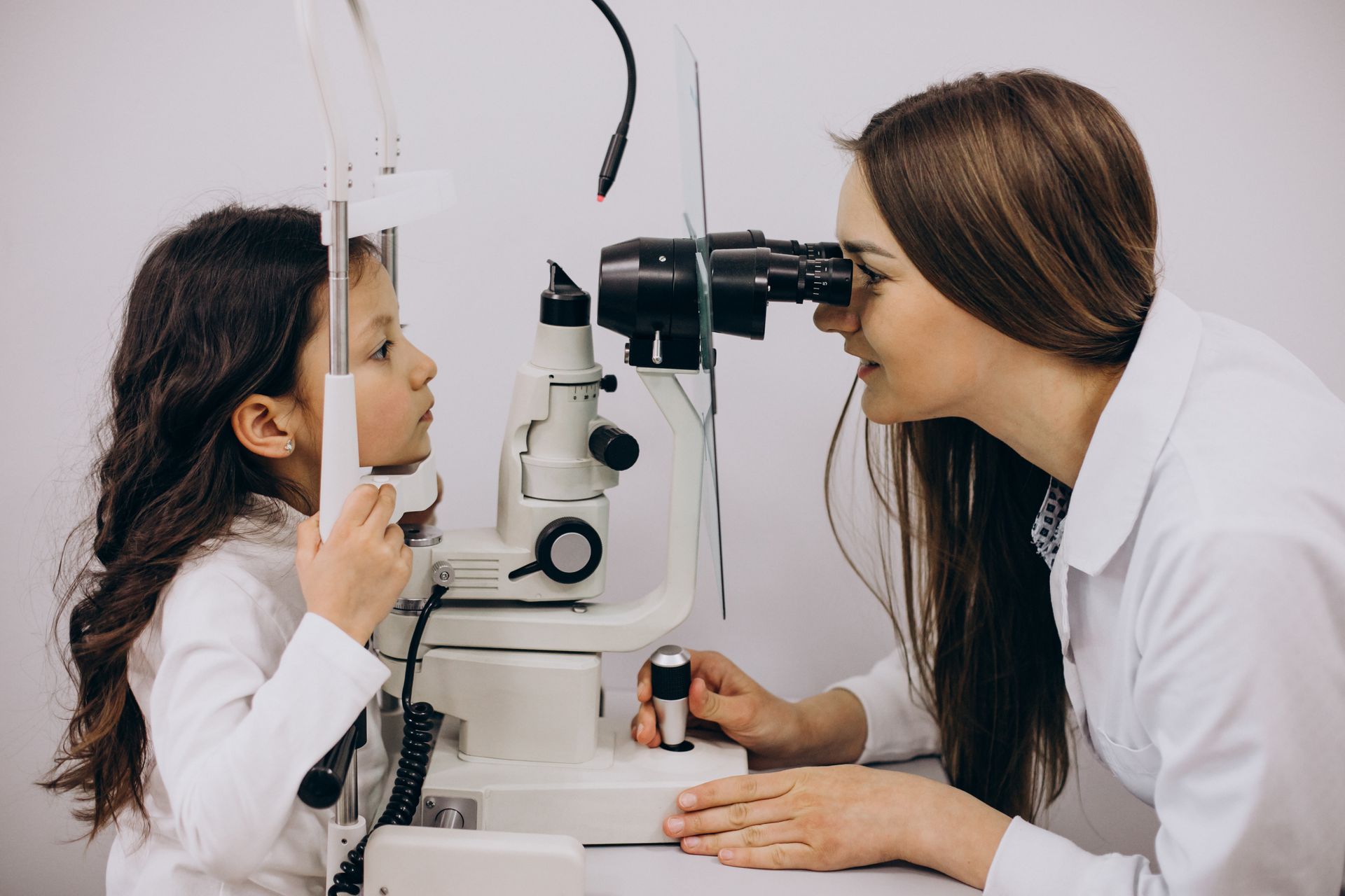 A little girl is getting her eyes examined by an ophthalmologist.