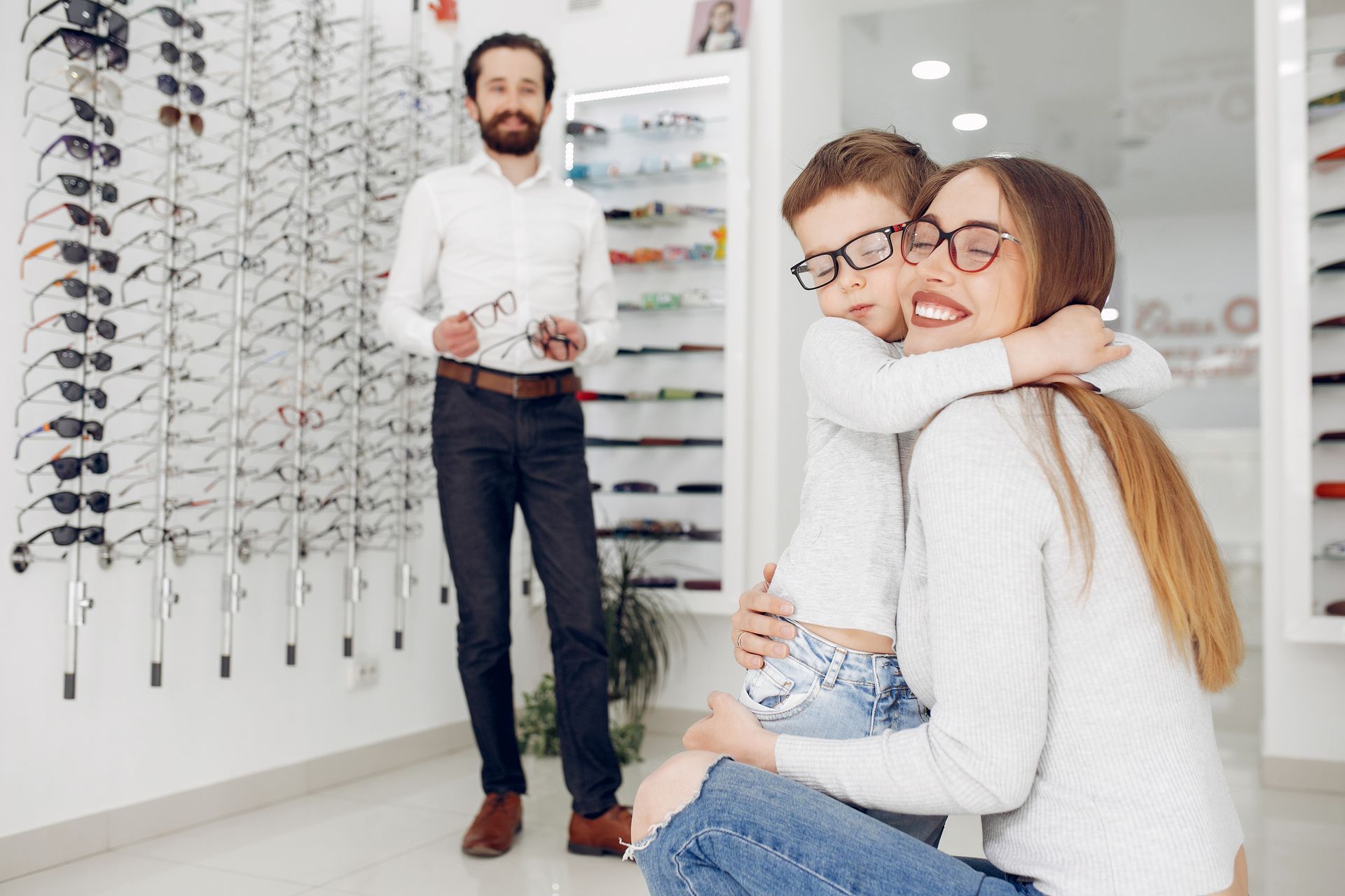 A woman is hugging a child in an optical shop.