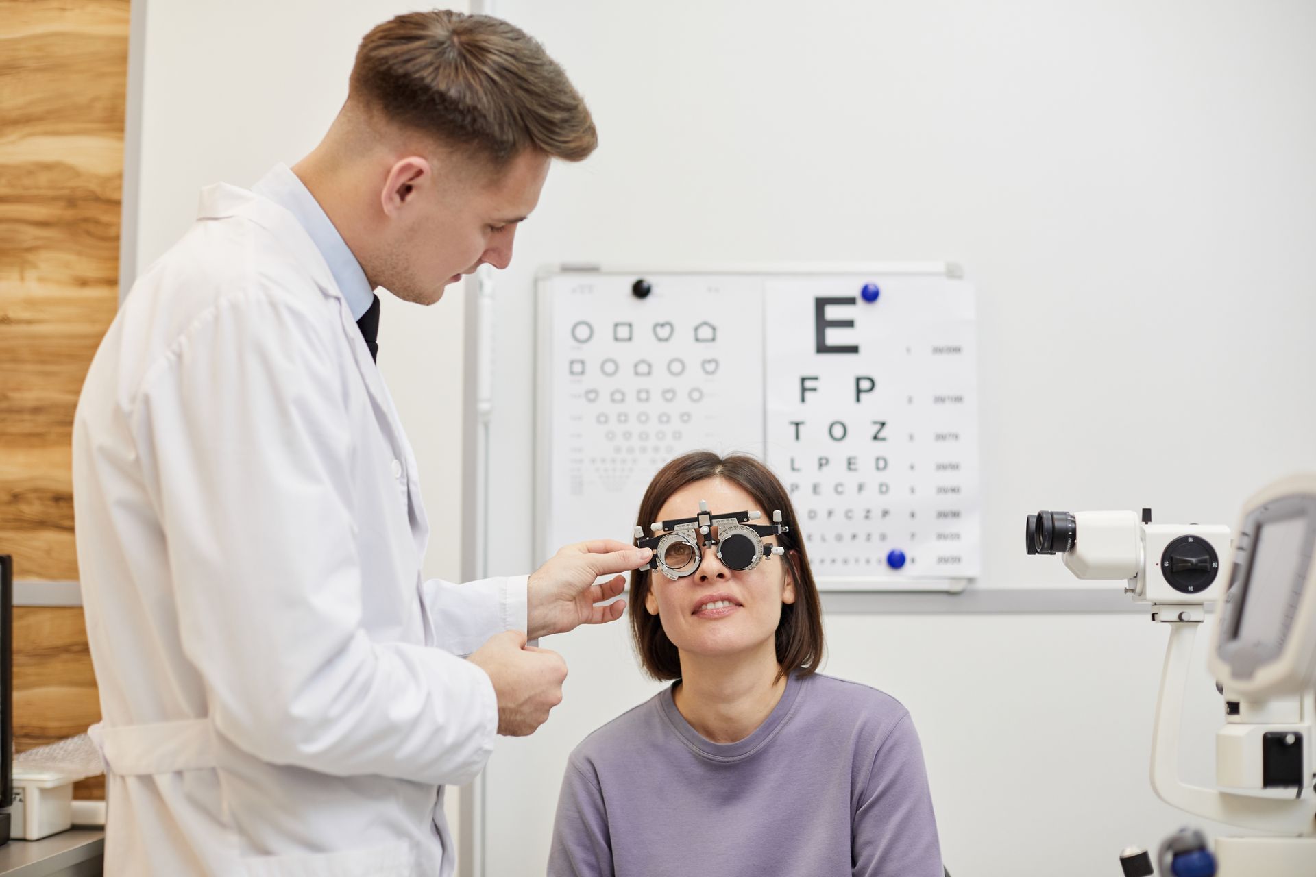 An ophthalmologist is examining a woman 's eye with a pair of glasses.