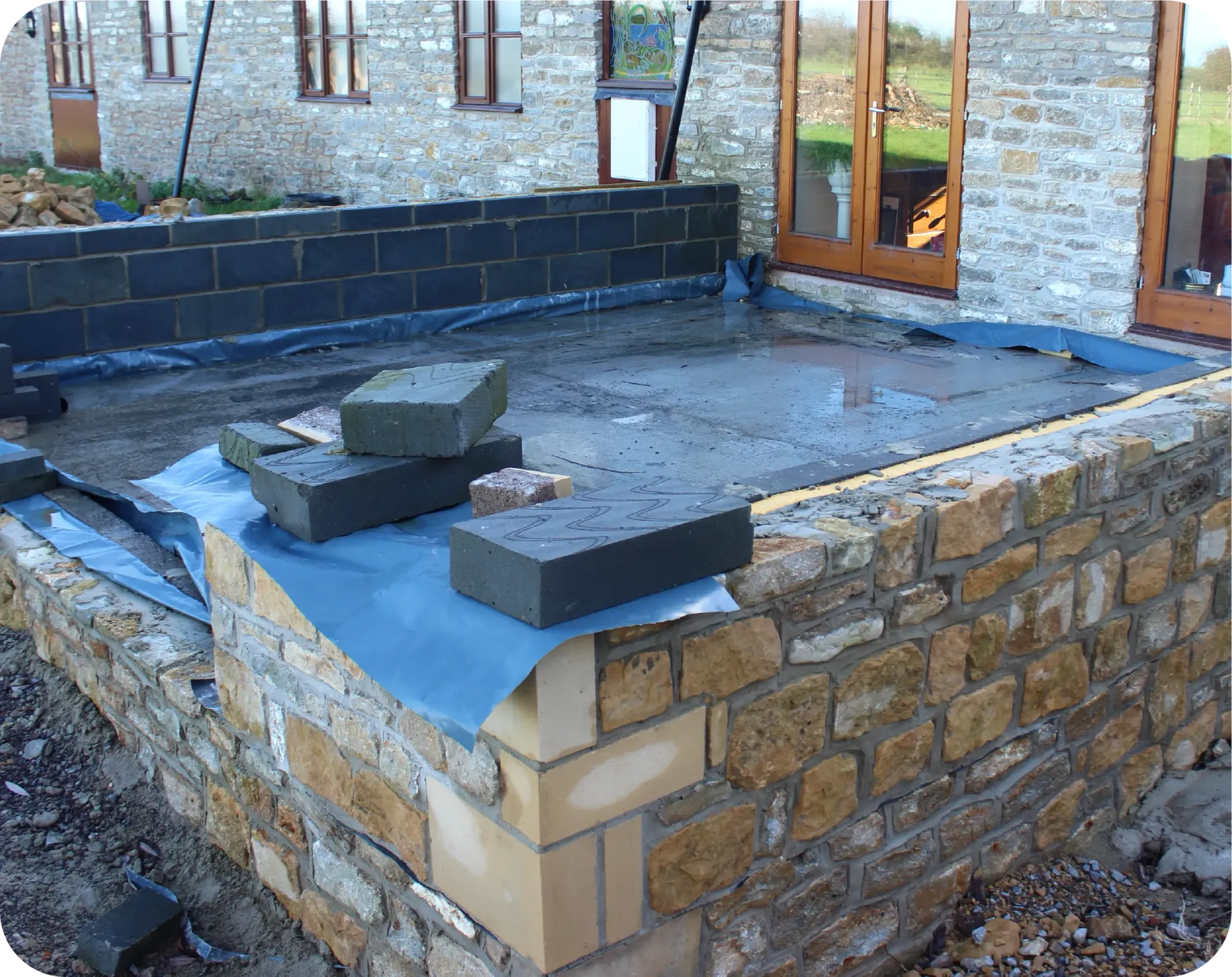 A man is sitting in a blue bucket on a crane.