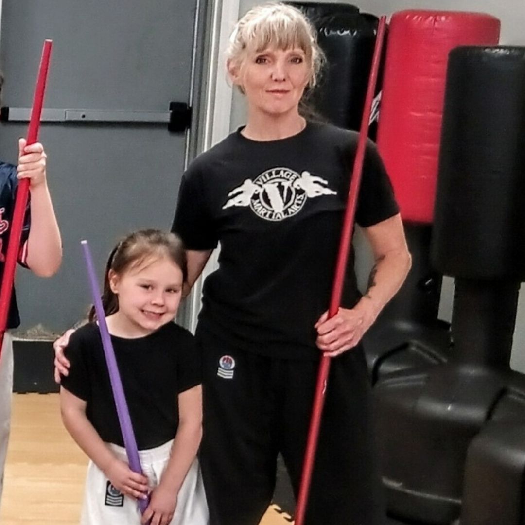 People practicing Brazilian Jiu-Jitsu. One person on the ground, another on top; two others grappling nearby. Black gis, indoor setting.