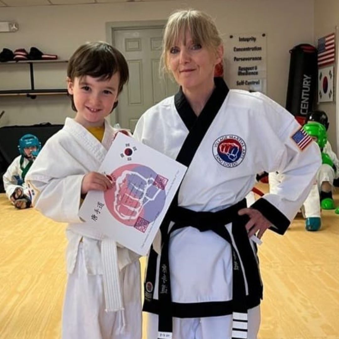Two children grappling on a mat, one in a headlock.