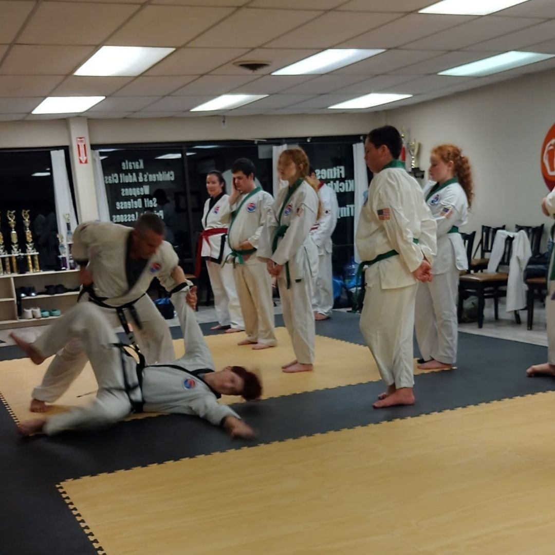 Two people practicing Brazilian Jiu-Jitsu on a mat. One is on top, applying a hold.
