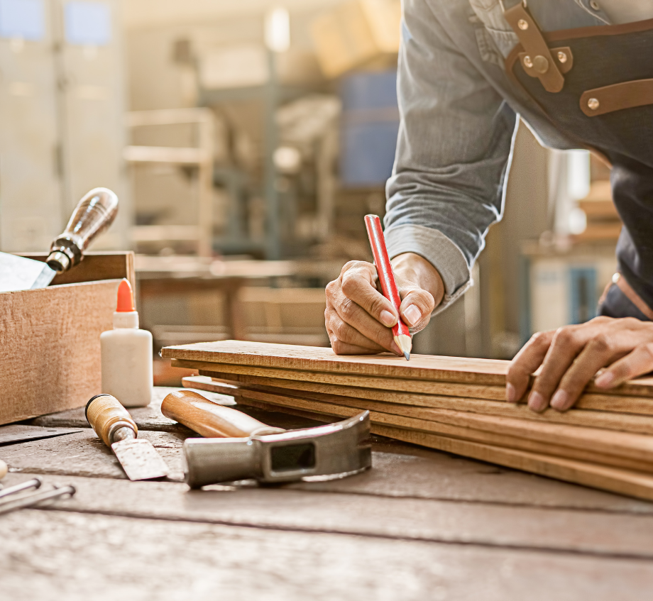 Un homme mesure un morceau de bois avec un crayon service de menuiseries