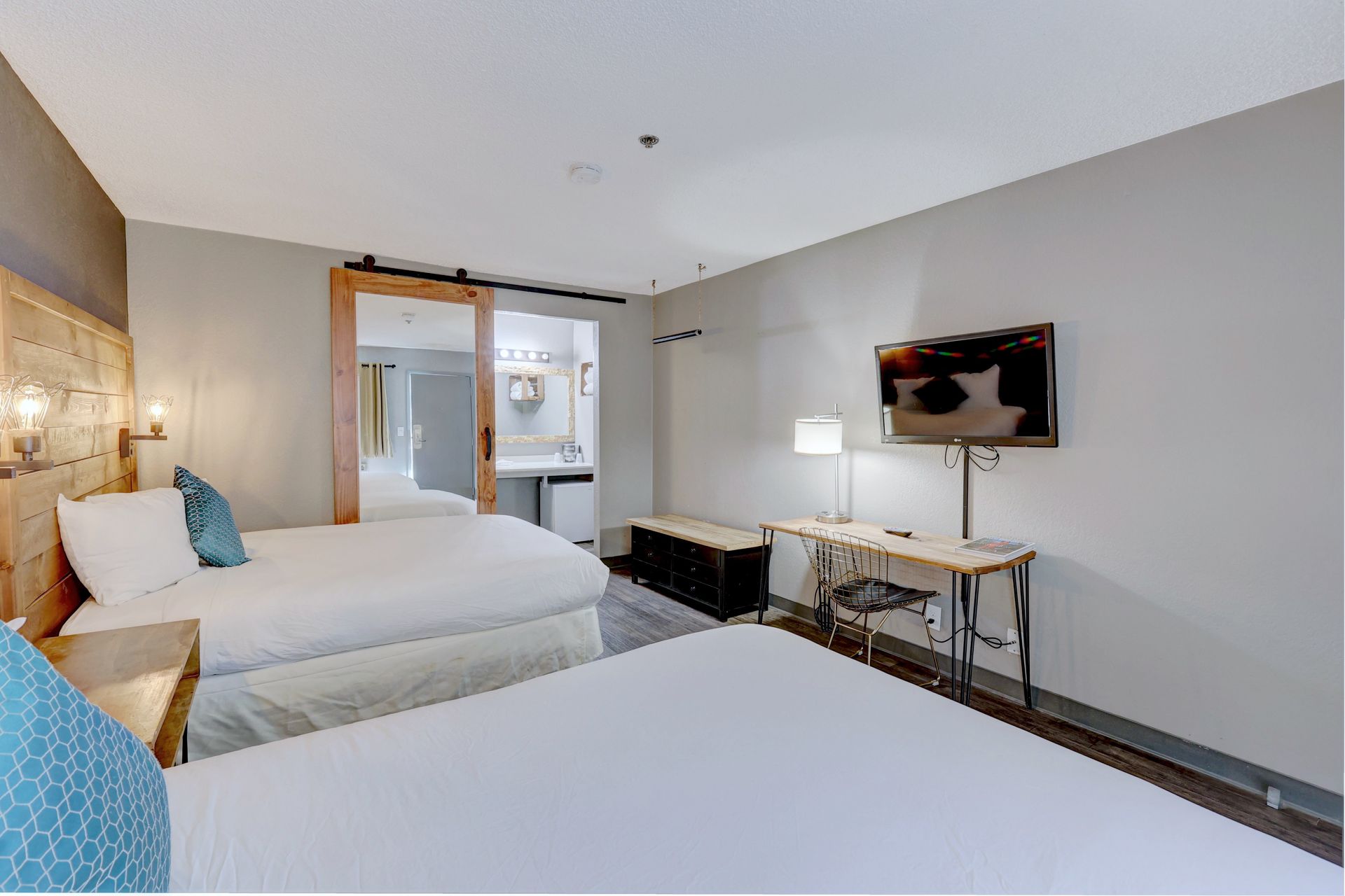 A hotel room with two beds , a desk , and a flat screen tv.