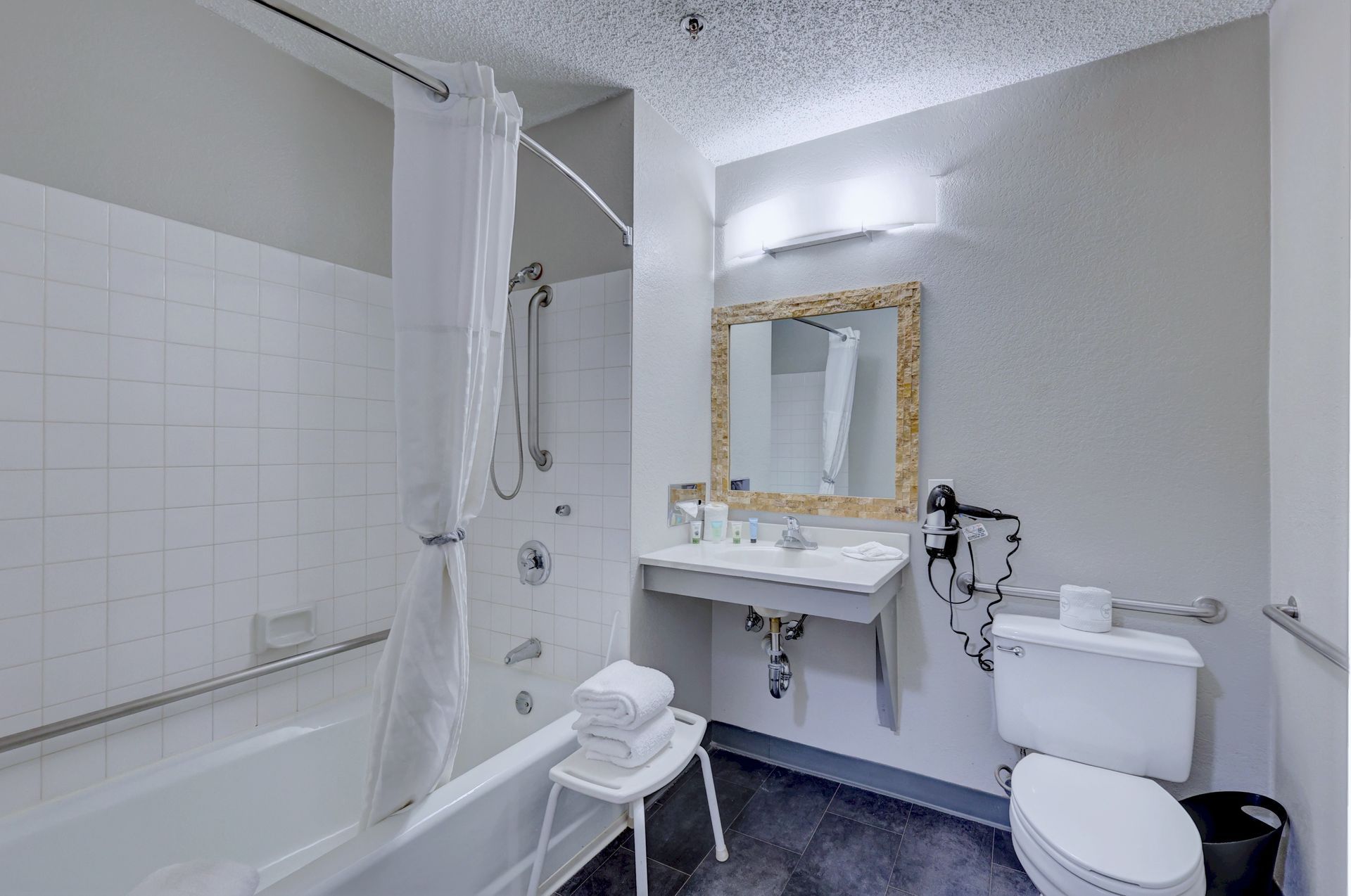 A bathroom with a tub , toilet , sink and mirror.