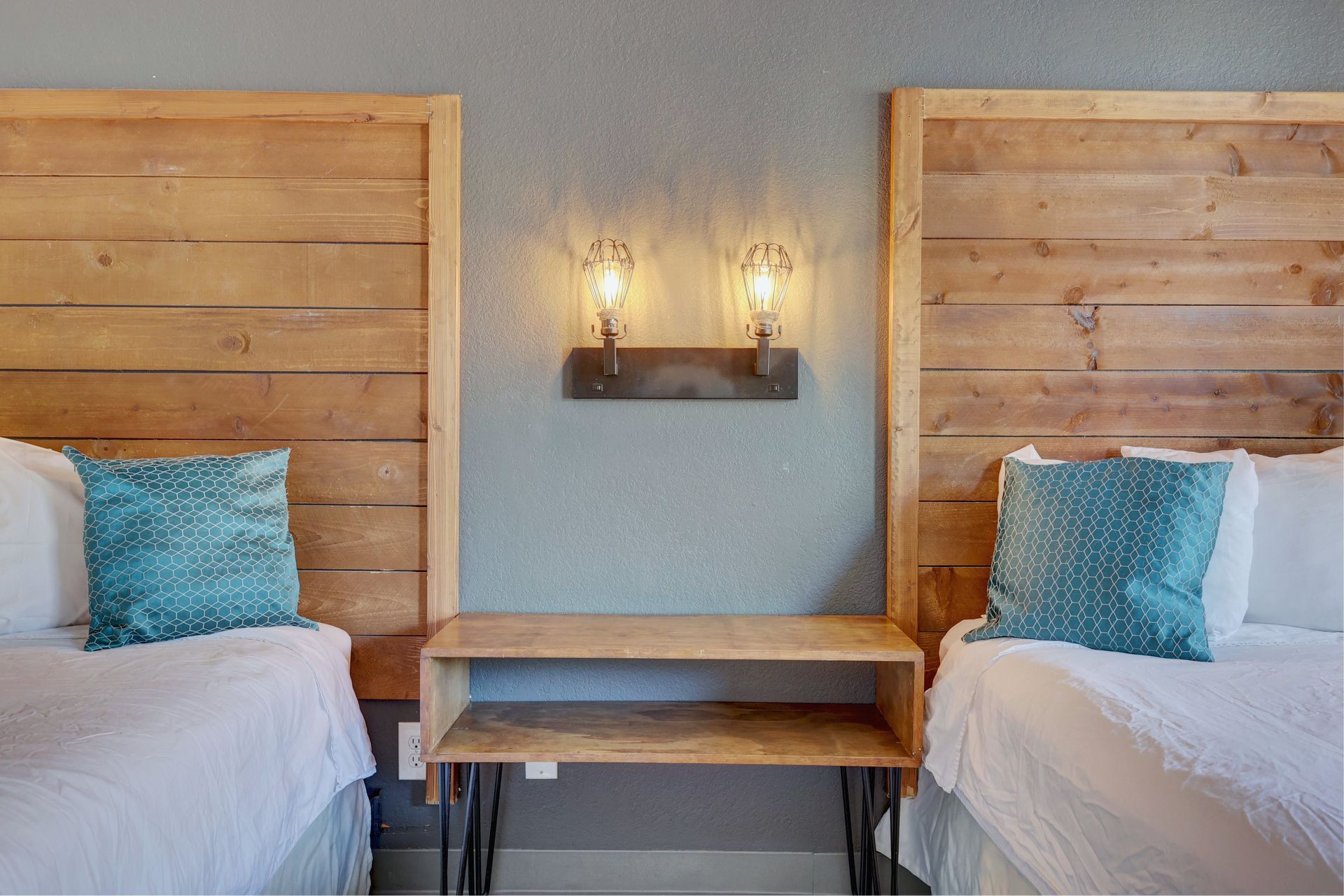 A bedroom with two beds , a nightstand , and two wooden headboards.