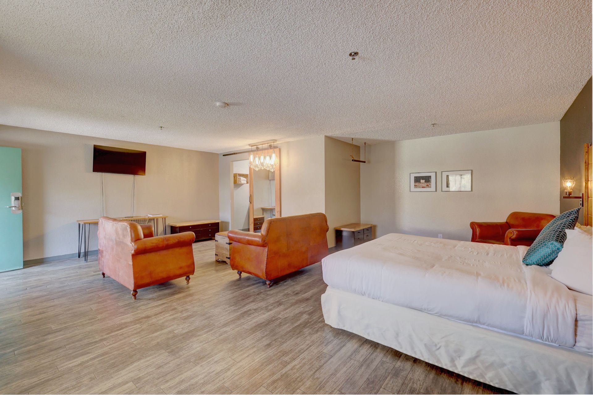 A hotel room with a king size bed , chairs , couch and television.