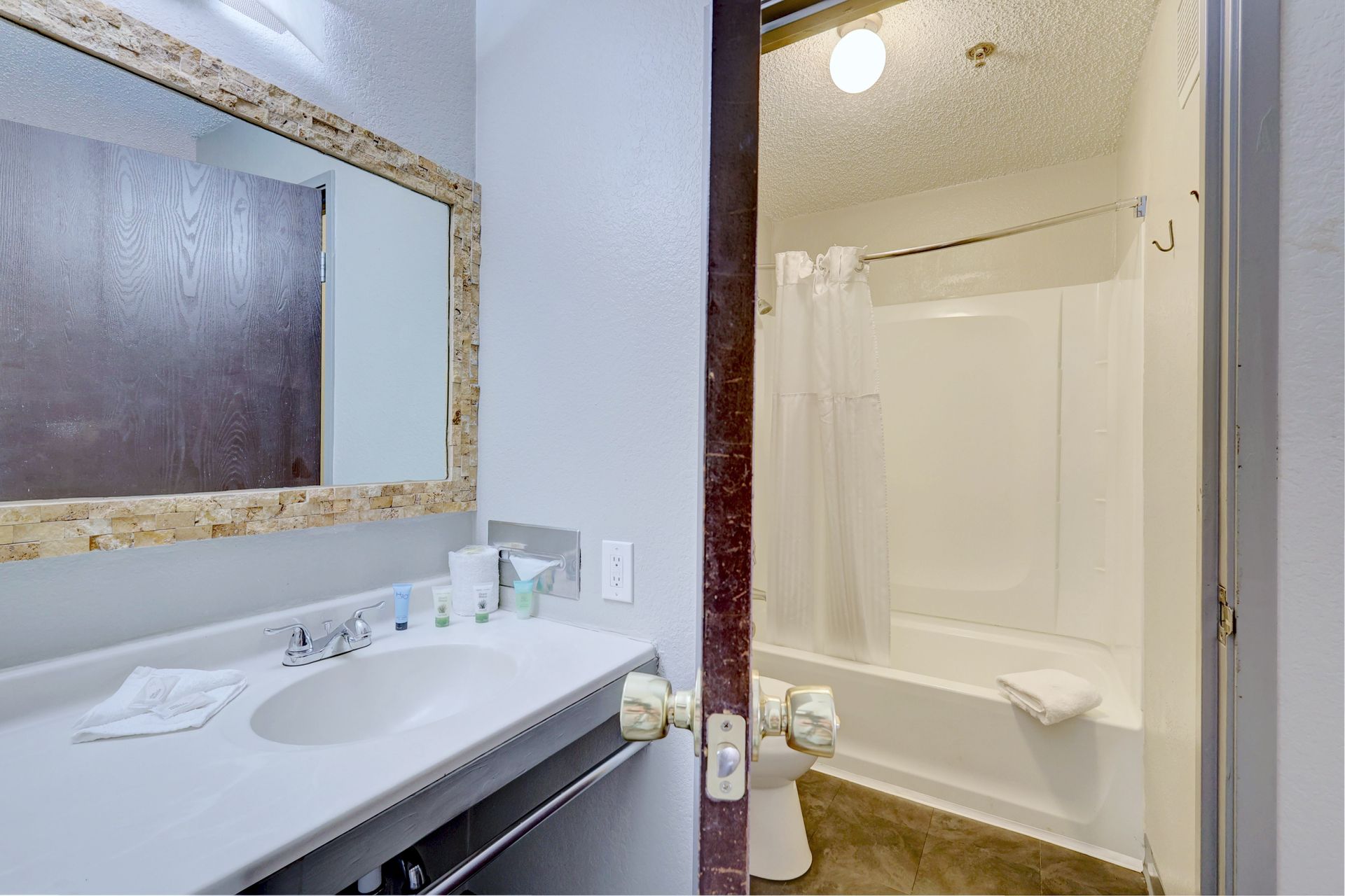 A bathroom with a sink , toilet , shower and mirror.