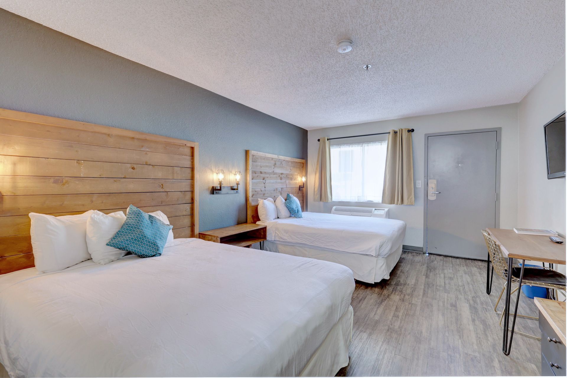 A hotel room with two beds , a desk , and a television.