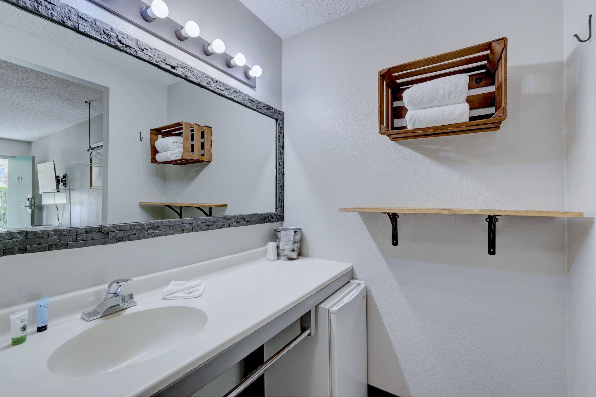 A bathroom with a sink , mirror and shelf.