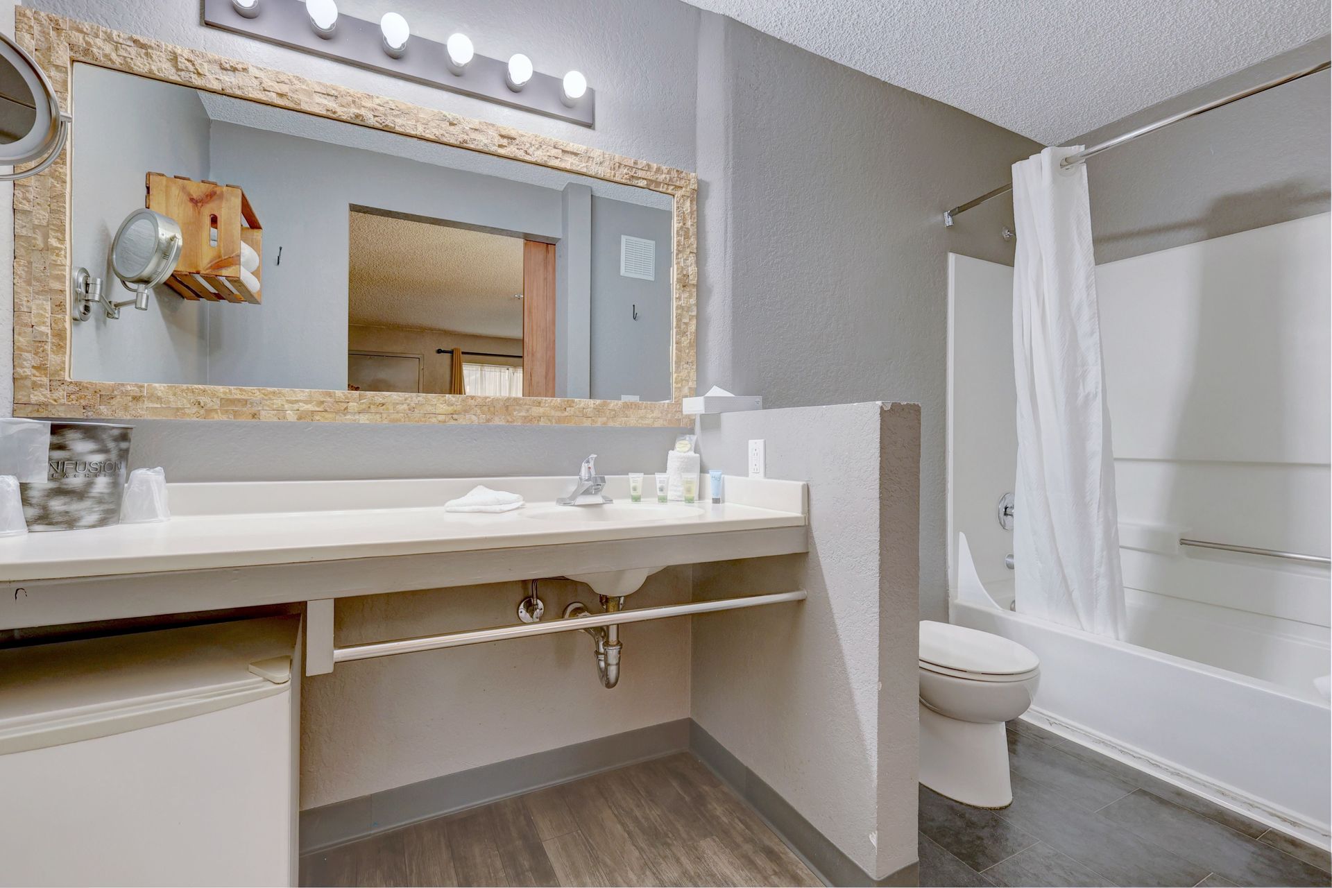A bathroom with a sink , toilet , shower and mirror.