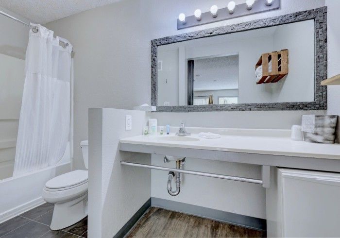 A bathroom with a toilet , sink , mirror and tub.