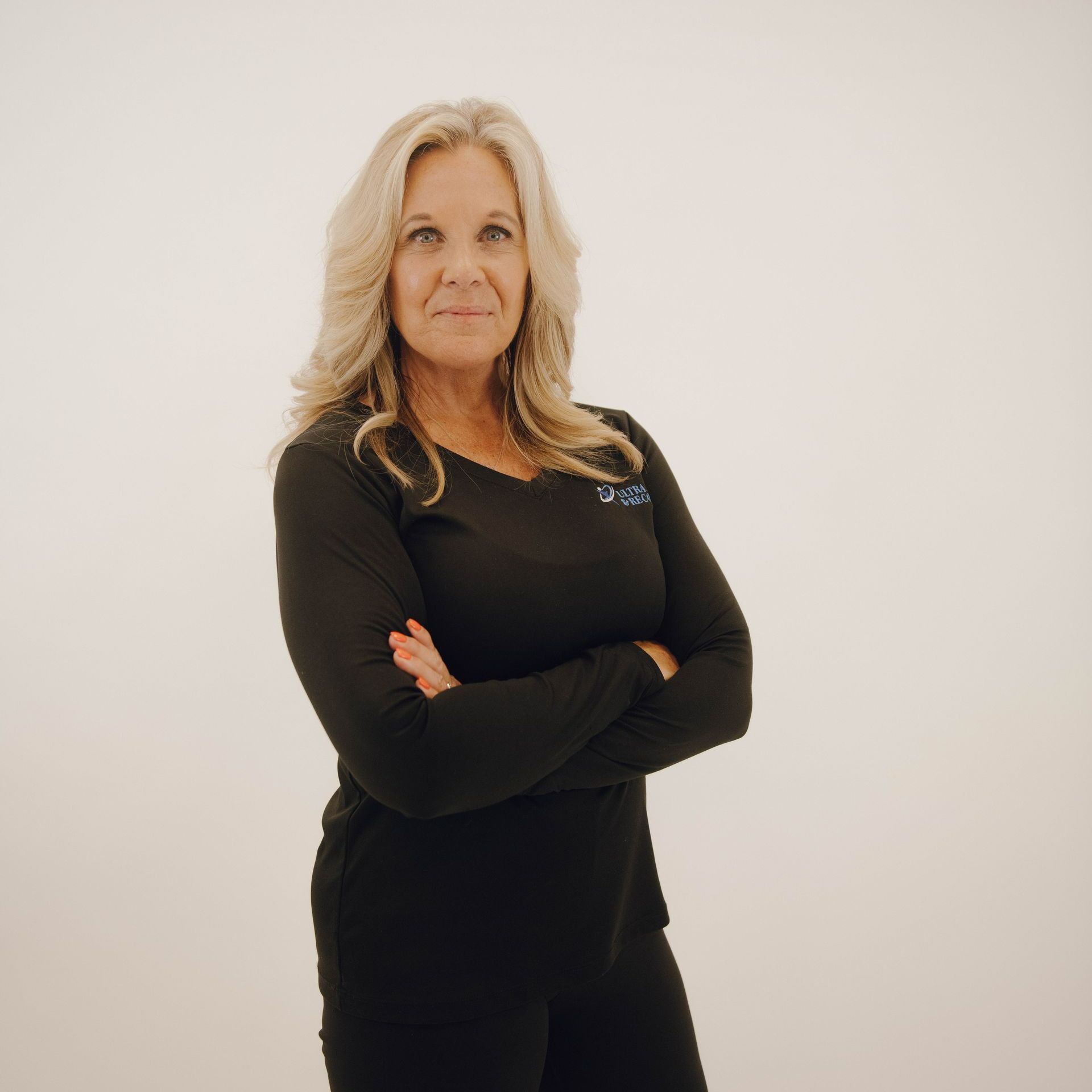 A woman in a black shirt is standing with her arms crossed