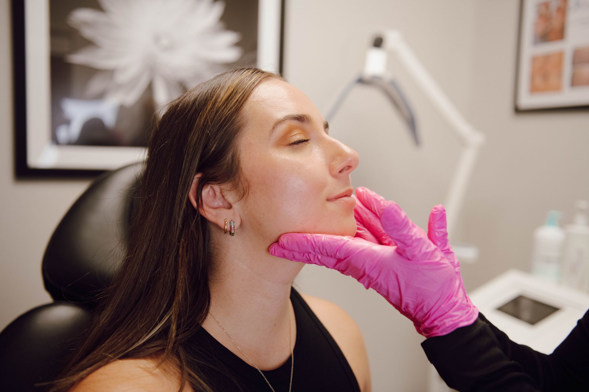 A Woman is getting her Face Examined by a Doctor wearing Pink Gloves — Auburndale, FL — Ultra Cryo & Recovery