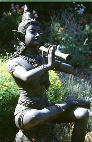 A statue of a woman playing a flute in a garden