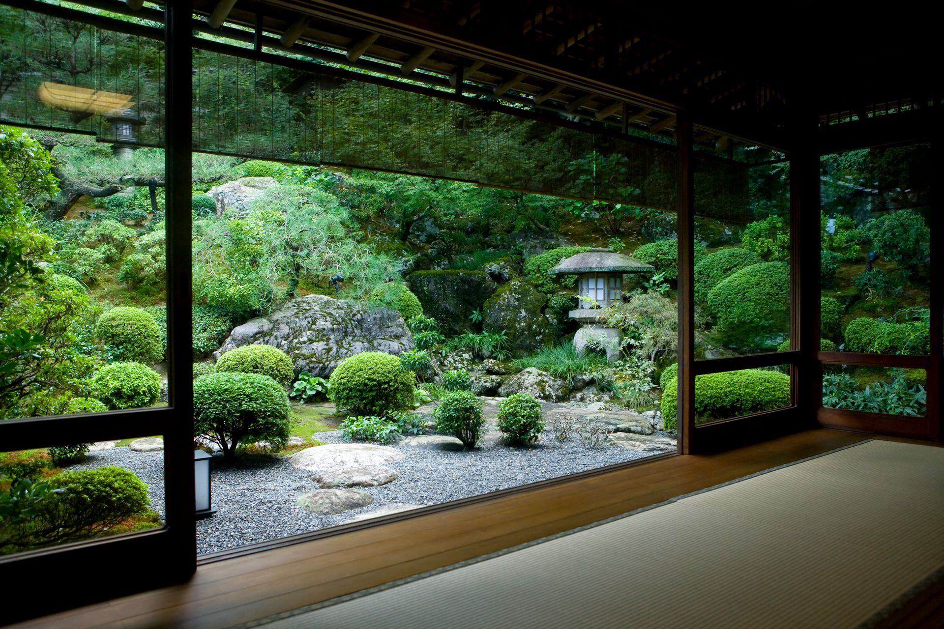 A room with a view of a garden through a window.
