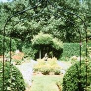 There is a metal arch in the middle of a garden.