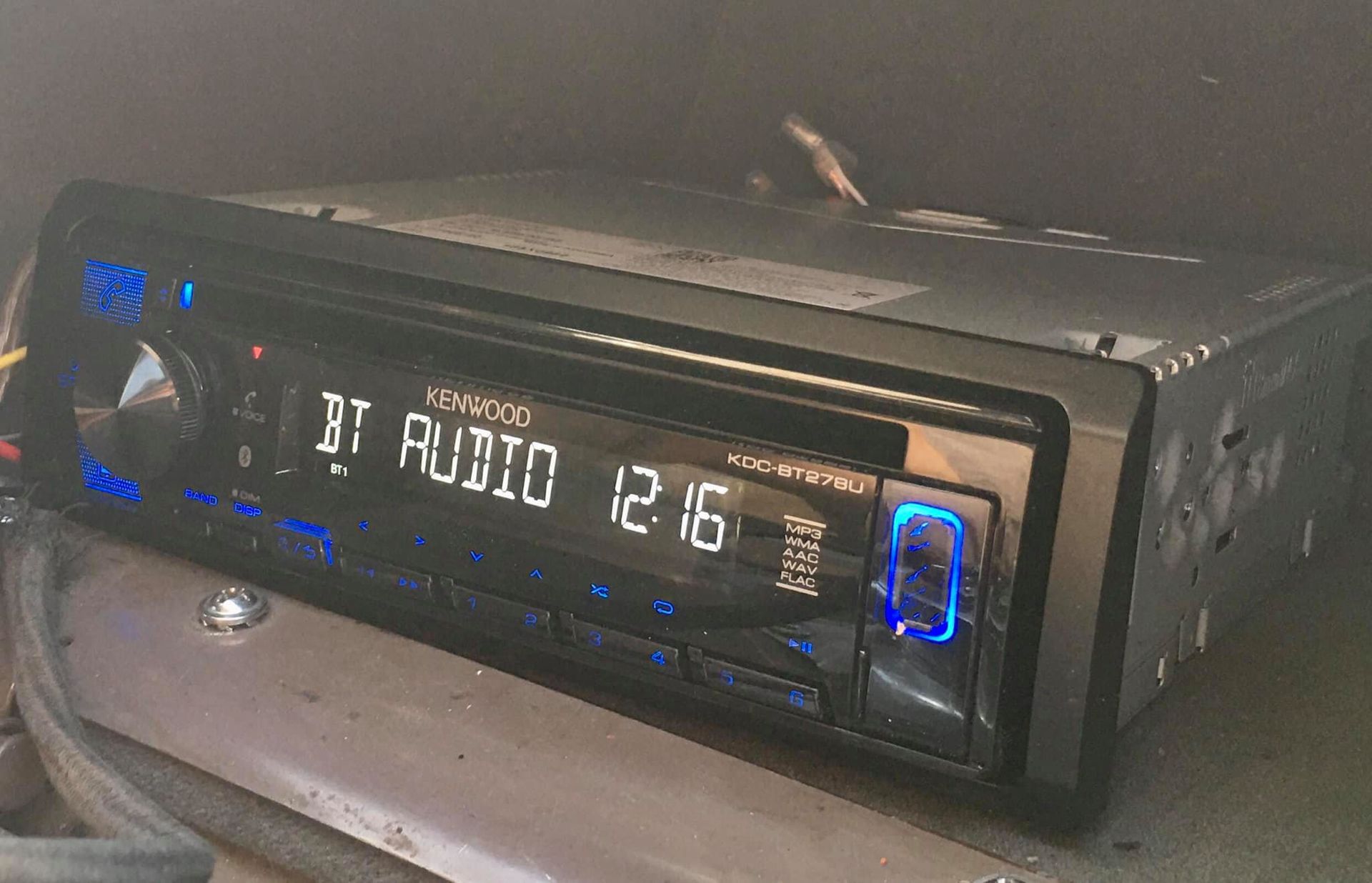 Car stereo with blue-lit buttons and display showing 