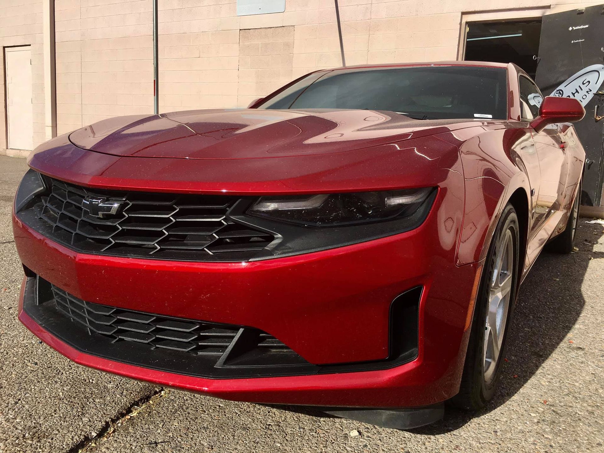 Red Chevrolet Camaro sports car parked in front of a brick building.