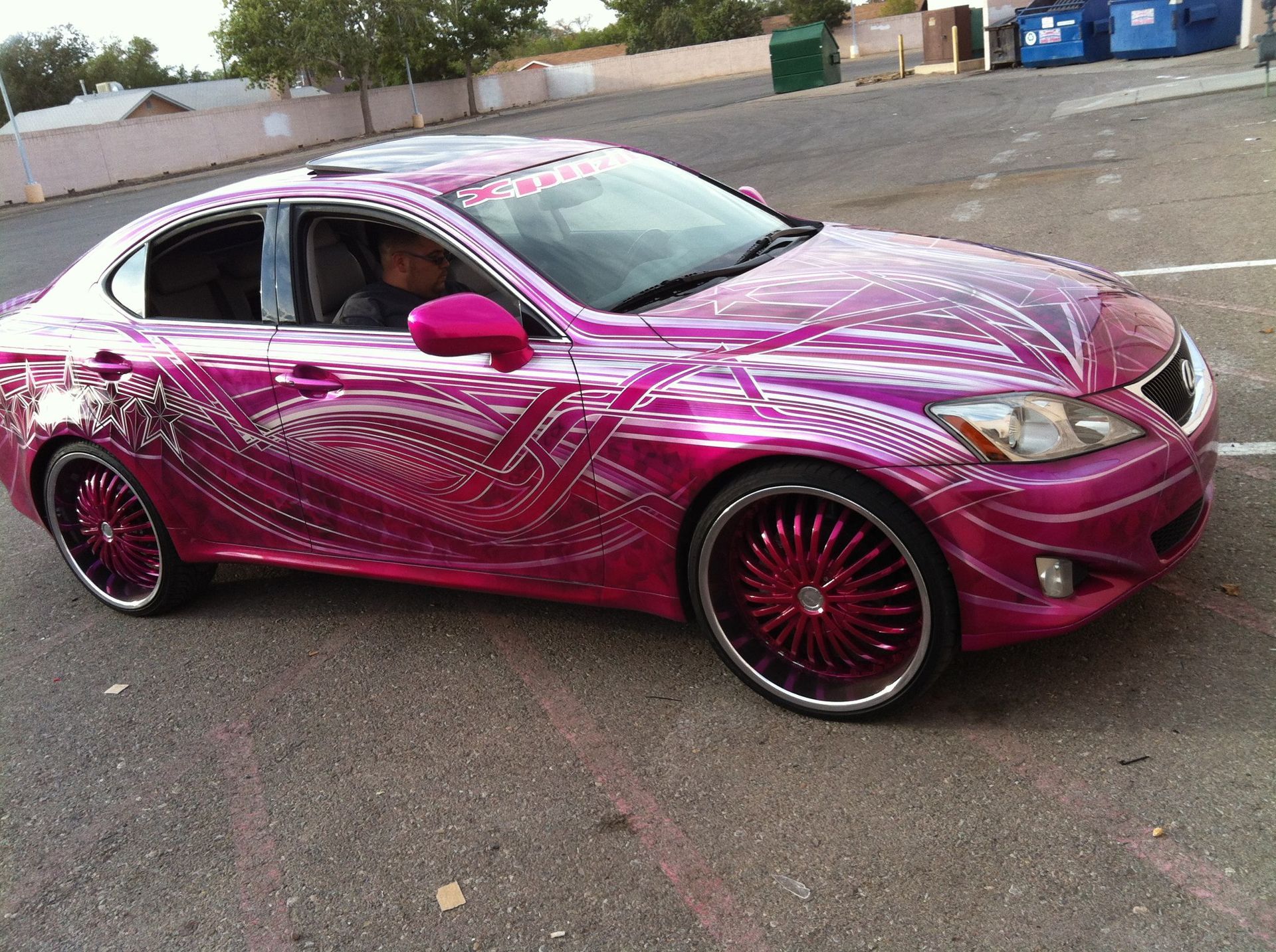 Pink Lexus sedan with custom paint and rims parked outdoors.