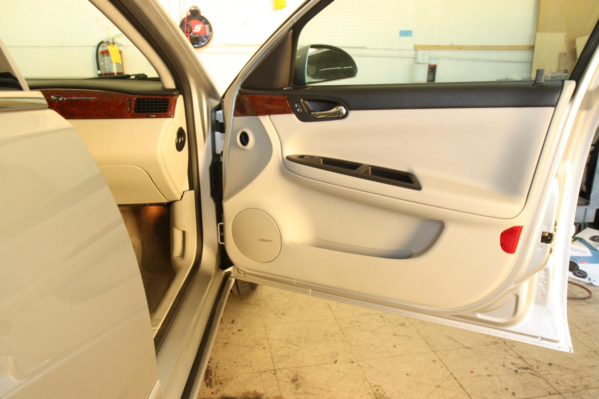 White car door open, interior visible. Speaker, wood trim, and door panel details.