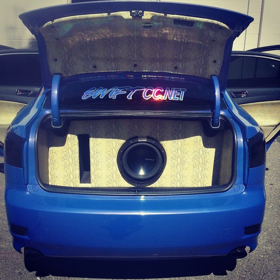 Blue car trunk with large subwoofer and custom audio setup; 