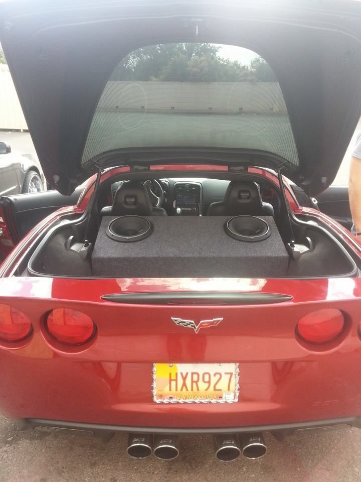 Red Corvette with the trunk open, showing a custom subwoofer setup.