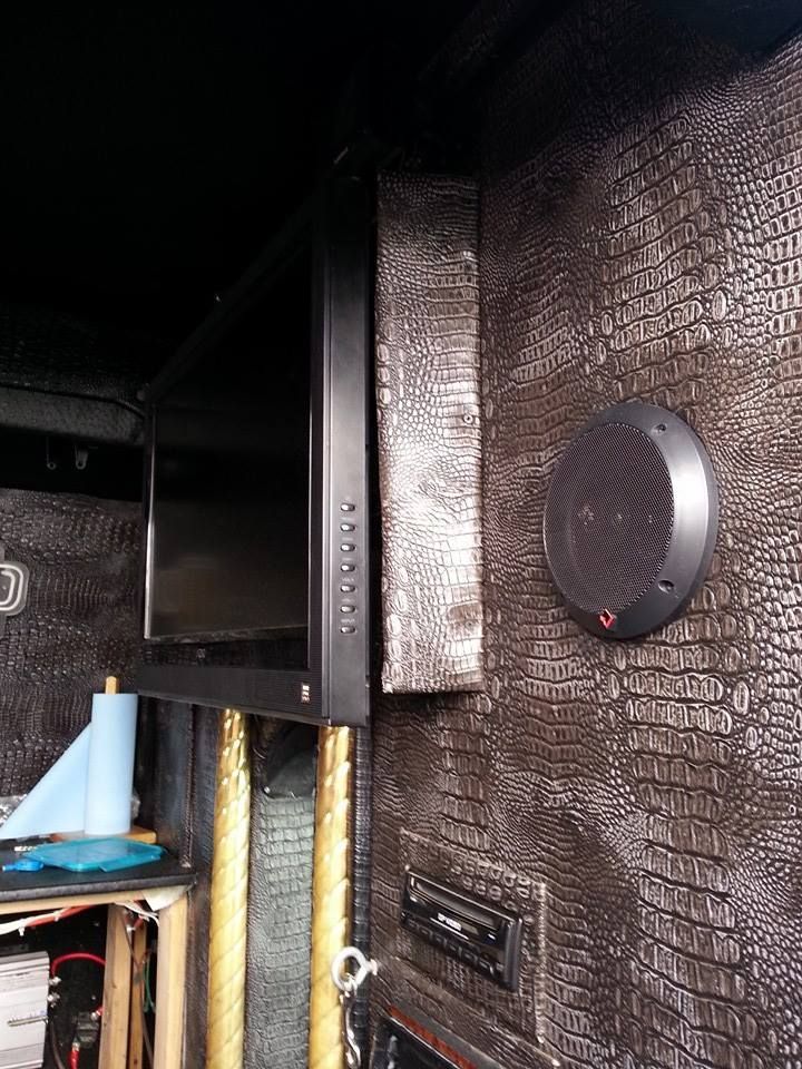 Black TV mounted in a room with a faux alligator skin wall, speaker, and stereo.