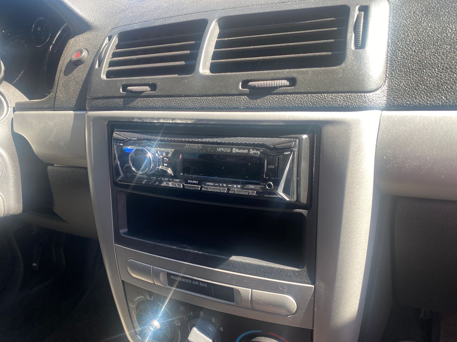 Car dashboard with aftermarket stereo and air vents.