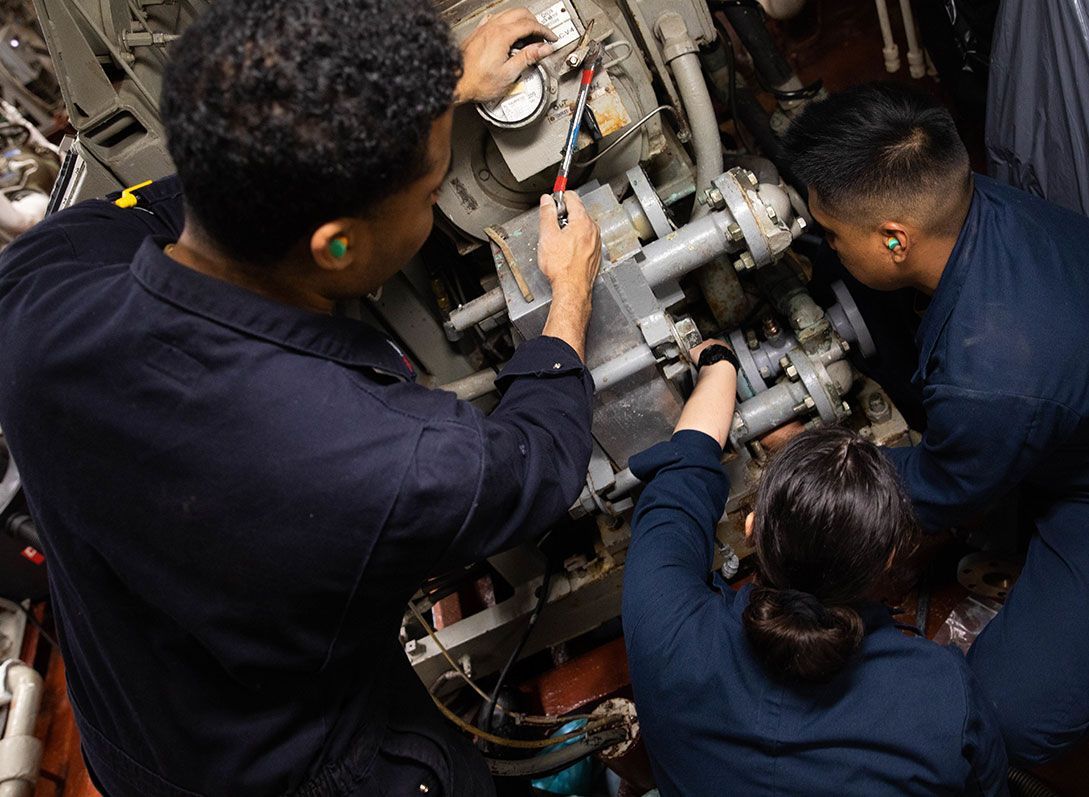 A group of people are working on a machine on a boat.