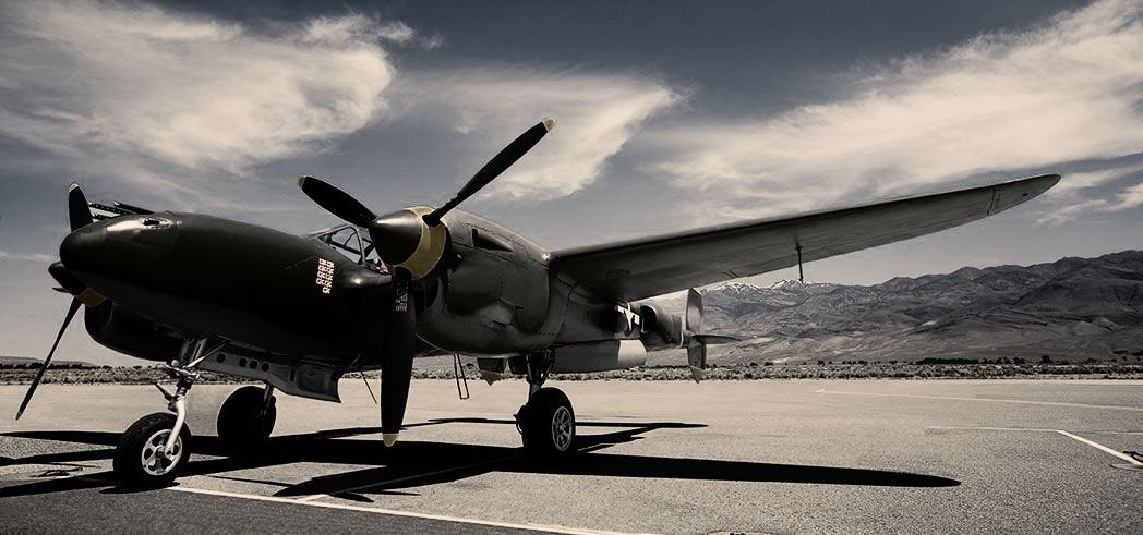 A black and white photo of a propeller plane on a runway.