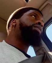 A man with a beard gazes toward the upper right, illuminated by sunlight through a window.