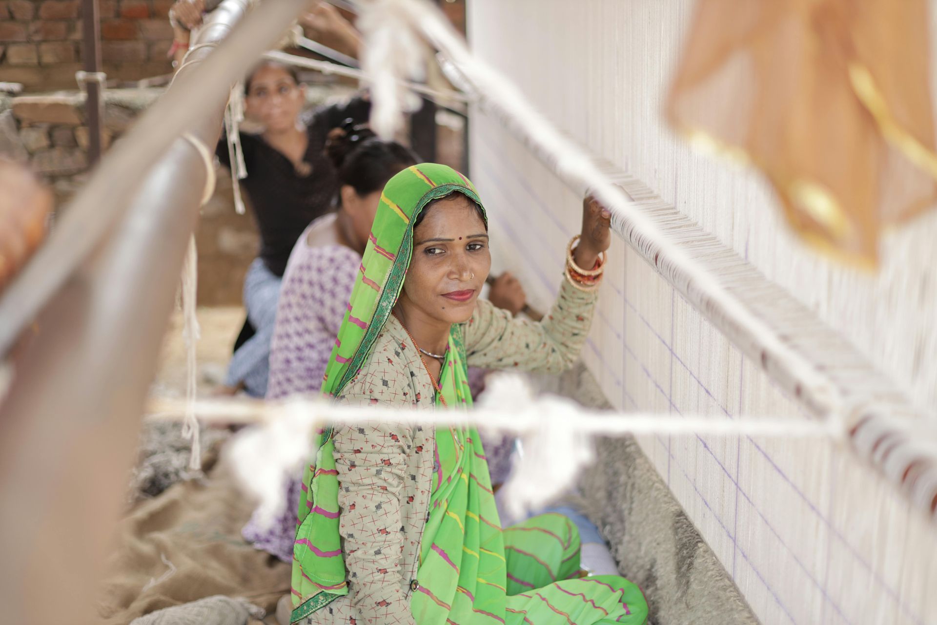 an indian woman seated and weaving textile