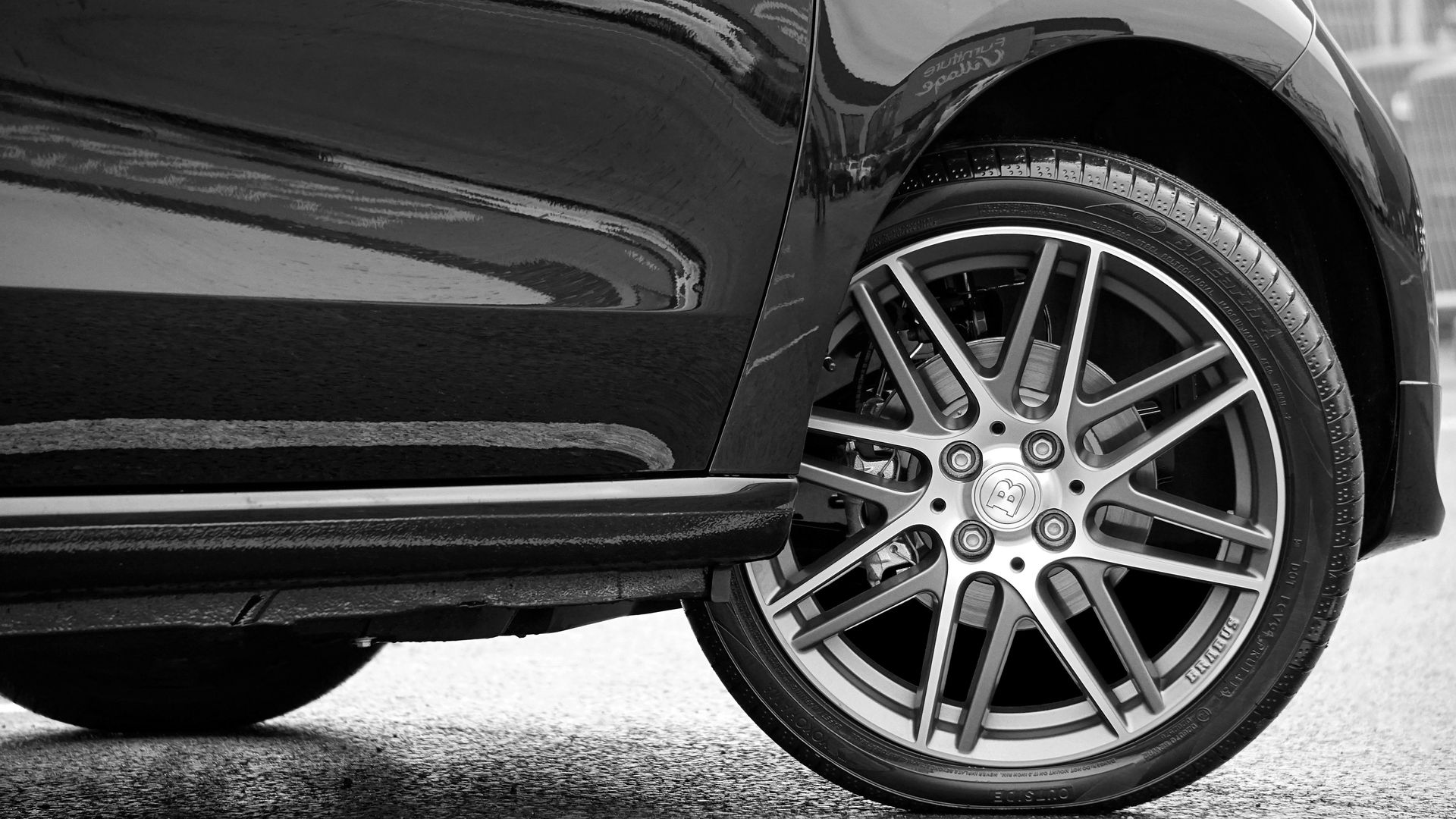 A black and white photo of a car 's wheel and tire.