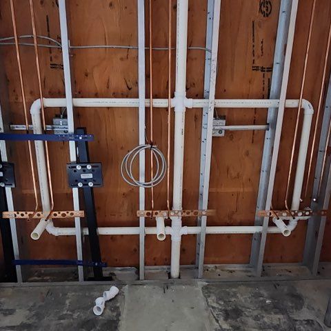 Woman in straw hat smiles, holding wine glass near a lake.