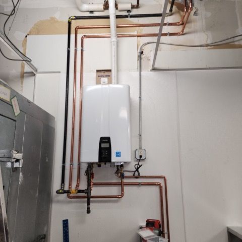 Woman in straw hat smiles, holding wine glass near a lake.