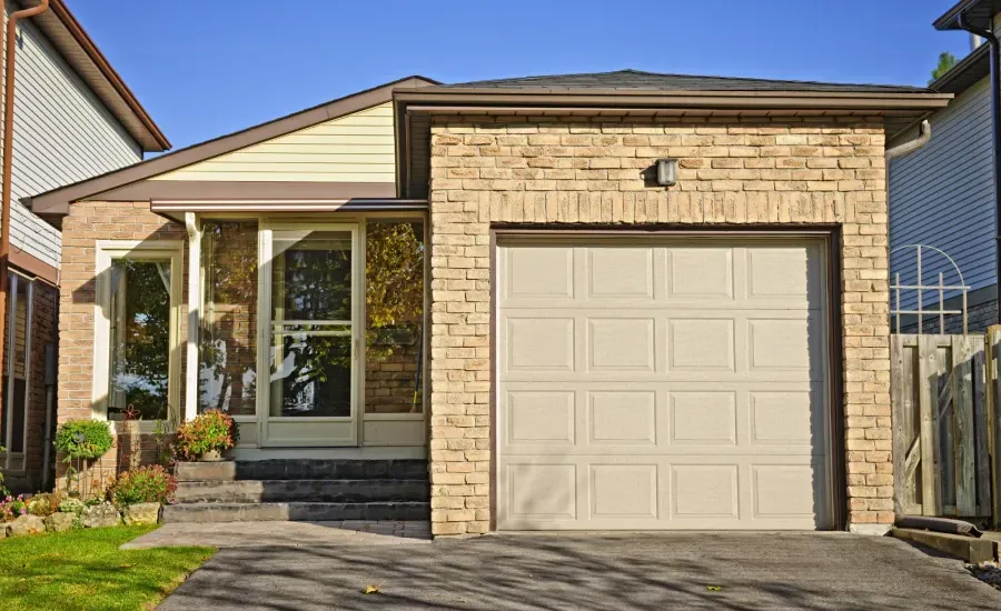 A brick house with a white garage door and a driveway.