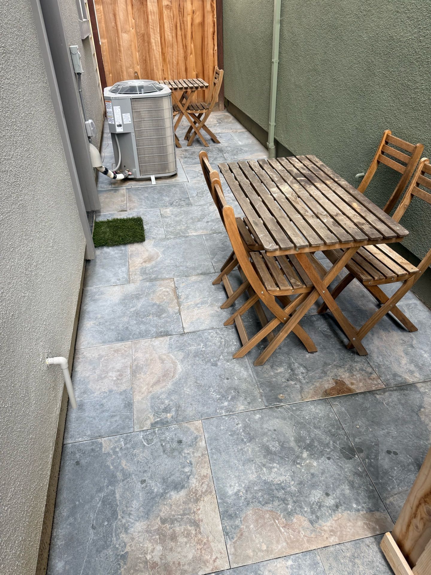 A patio with a table and chairs and an air conditioner.