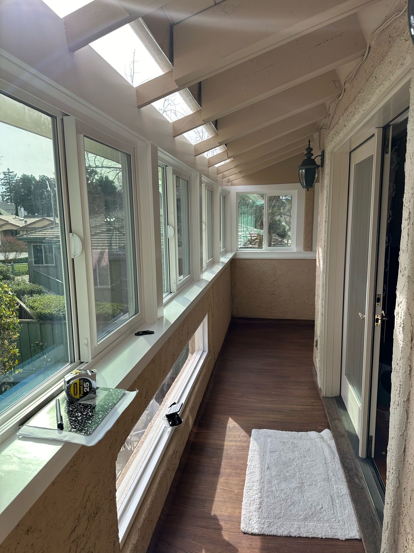 A long hallway with a lot of windows and a rug on the floor.