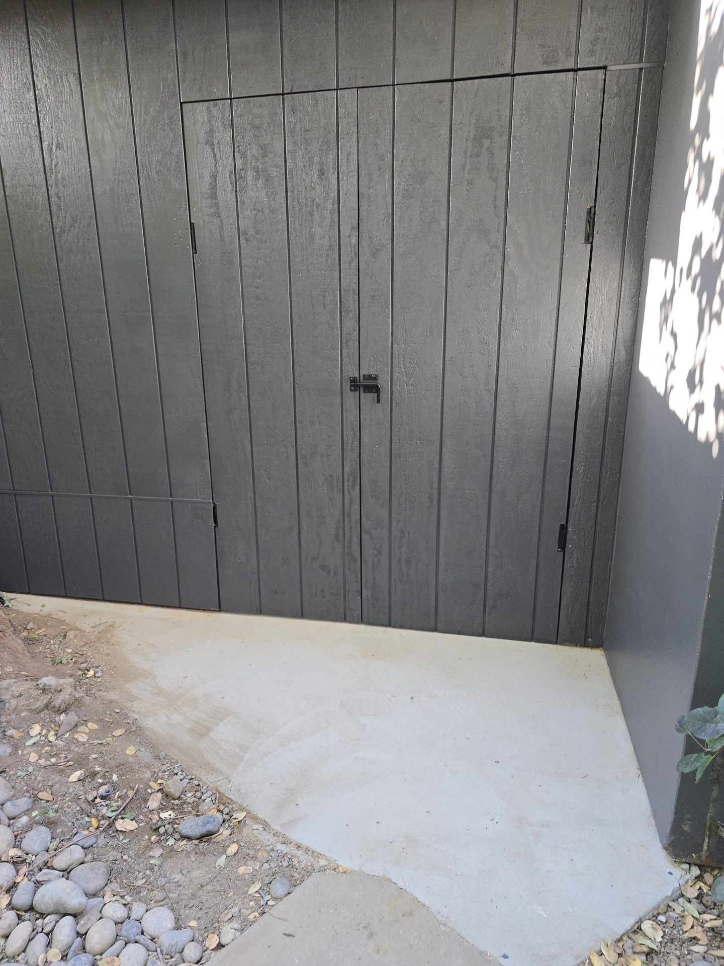 A gray garage door is sitting next to a concrete walkway.