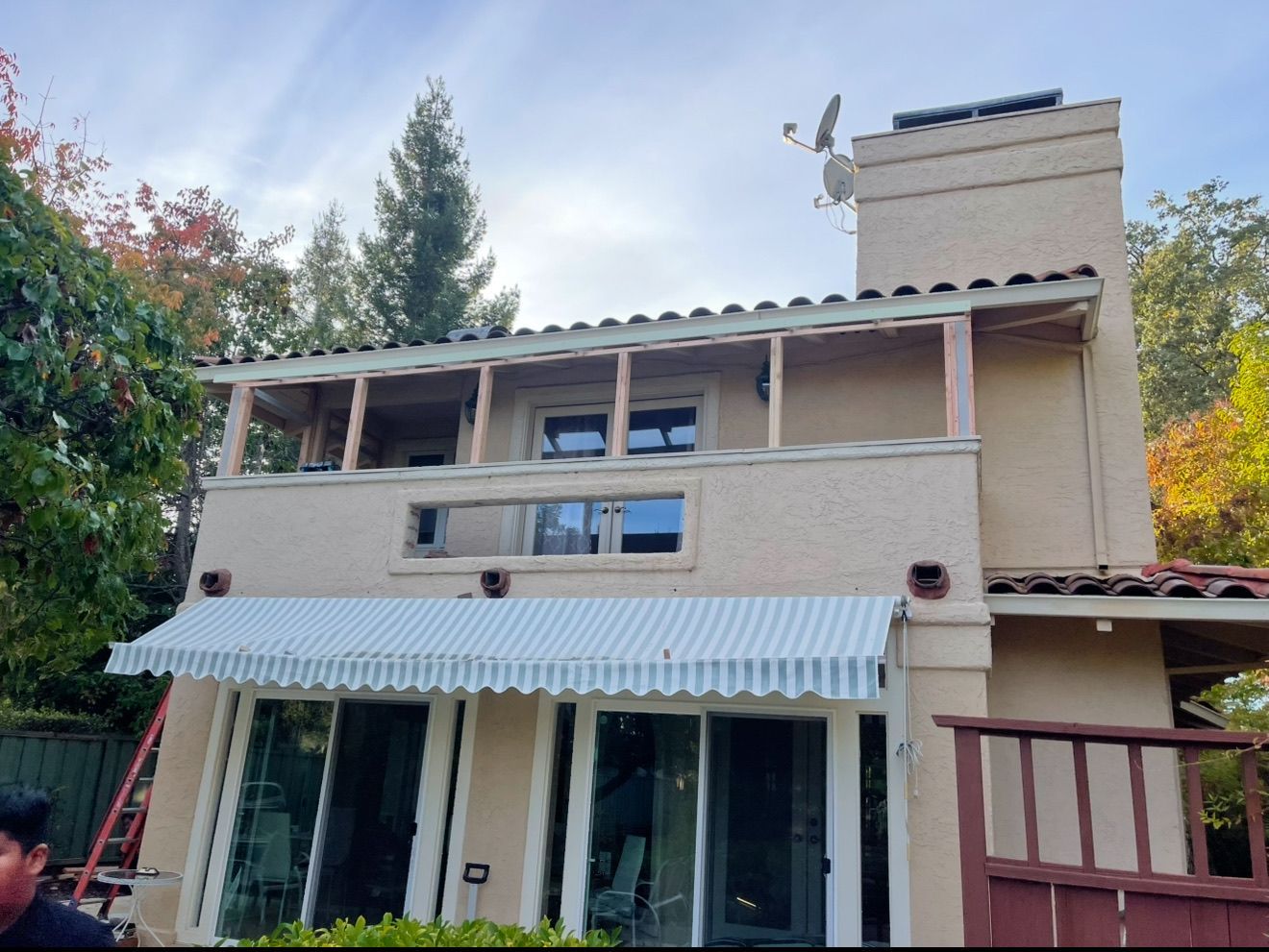 A man is standing in front of a house with a white awning.