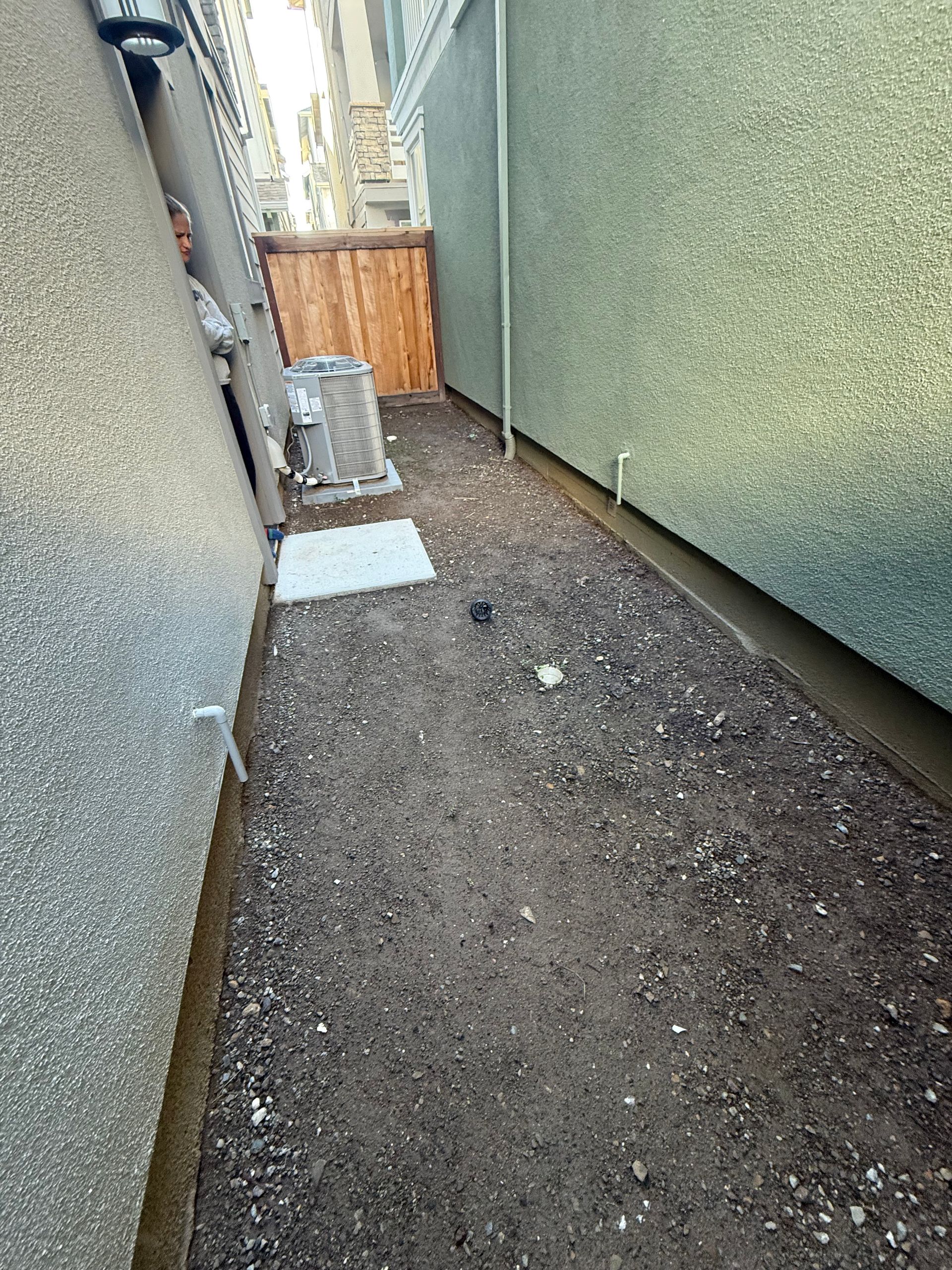 A narrow alleyway between two buildings with dirt on the ground.