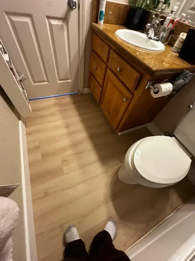 A bathroom with a toilet , sink , and wooden cabinets.